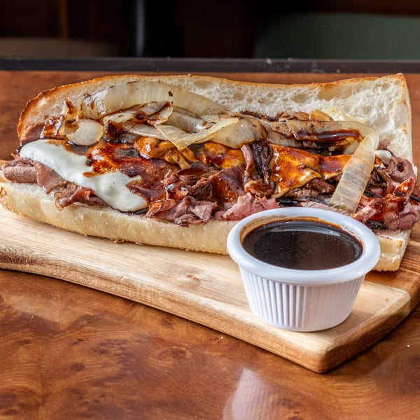 John's Deli French dip sandwich with roast beef, melted cheese, caramelized onions, and au jus.