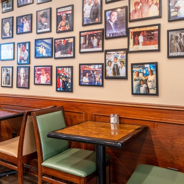 John's Deli interior with framed celebrity photos on the wall above booths and tables.