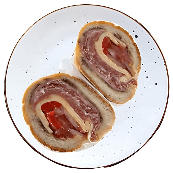 Two halves of a deli sandwich with meat, cheese, and tomatoes on a white plate.