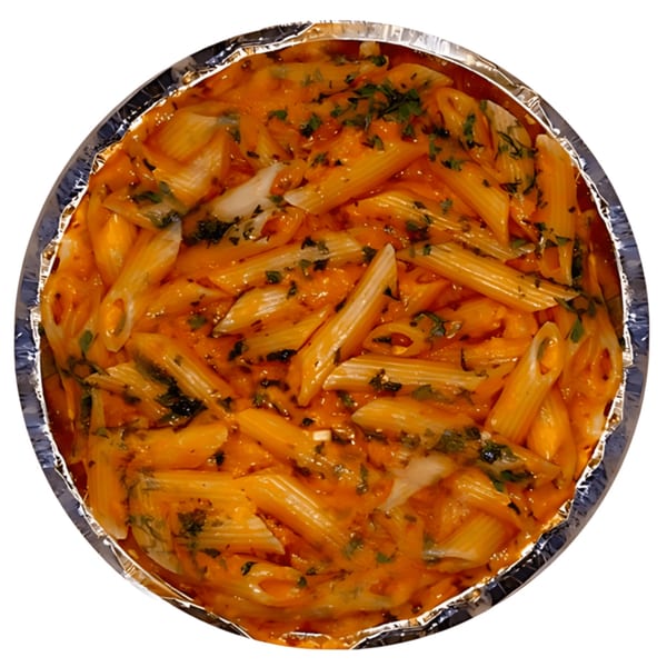 Penne pasta in a creamy orange sauce with green herbs, served in a foil container.